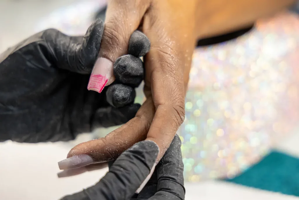 Close-up of a student learning advanced nail sculpting and shaping an acrylic nail at Apex Beauty Academy.